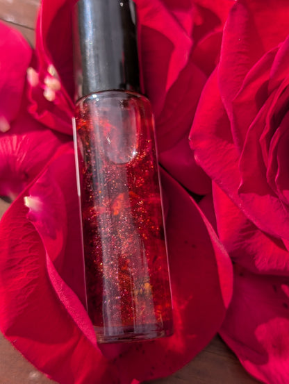 Pomba Gira roll-on ritual oil displayed with red roses